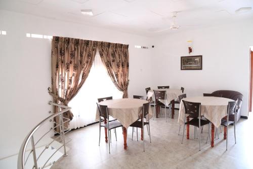 een eetkamer met tafels en stoelen en een raam bij Yaarl Holiday in Jaffna