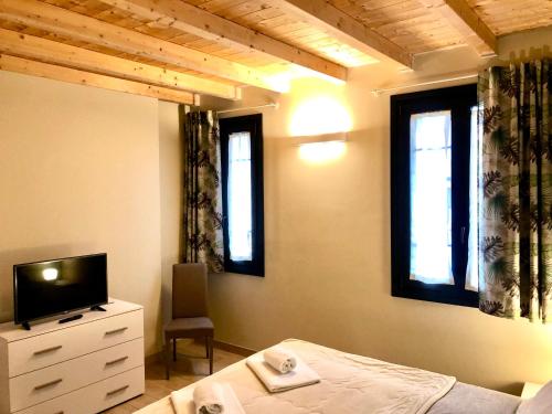 Schlafzimmer mit einem Bett, einem TV und Fenstern in der Unterkunft Residenza La Corte in Pizzighettone
