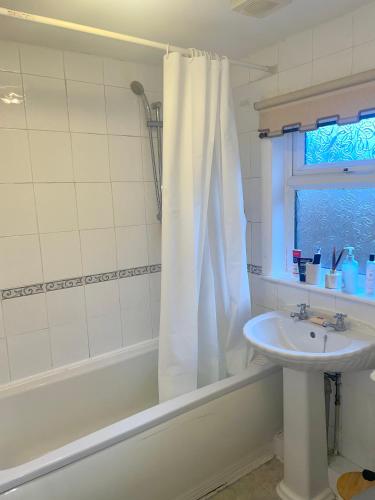 a bathroom with a sink and a tub and a shower curtain at Relaxing Crewe home in Crewe