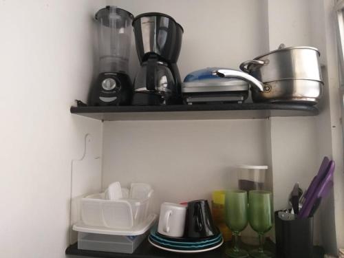 un estante con tazas y otros artículos de cocina. en Copa Studio near the sea, en Río de Janeiro