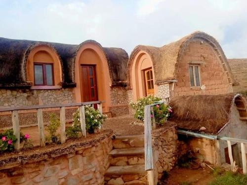 una casa antigua con techo de paja y escaleras en Hostal Qhana Pacha, en Isla de la Luna