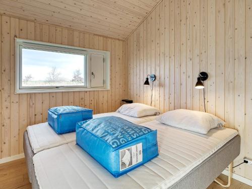 2 camas en una habitación con paredes de madera y ventana en Holiday home Rødby LV en Rødby