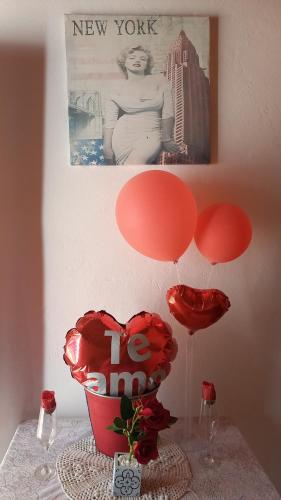 una mesa con globos rojos y un jarrón con corazones en Hospedaje Luque, en Luque