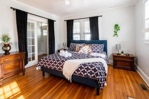 a bedroom with a bed and two dressers and windows at Globetrotters Suite in Historic Richmond with Patio in Richmond