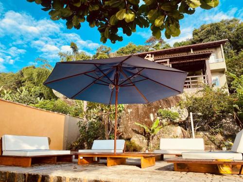 une table en bois avec deux chaises et un parasol dans l'établissement La Coquille, à Praia de Araçatiba