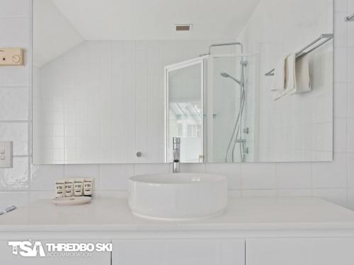 a white bathroom with a sink and a mirror at Wintergreen 5 in Thredbo