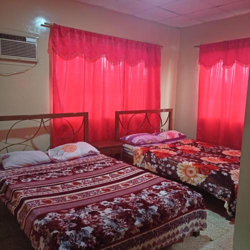 two beds in a room with pink curtains at HOTEL PRIMAVERA in Guayaquil