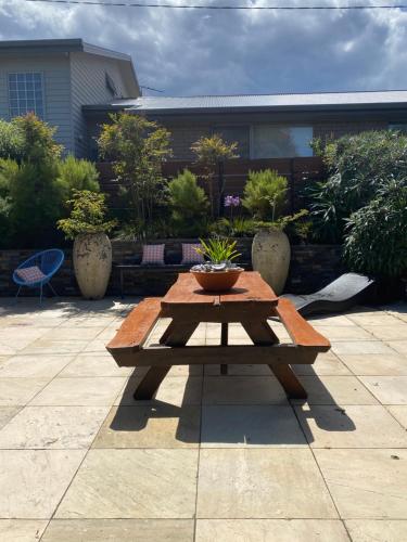 a wooden picnic table with a potted plant on it at Beach Buoy Opossum Bay in South Arm