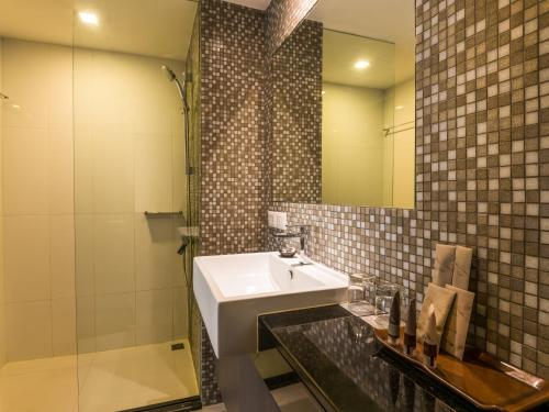 a bathroom with a sink and a shower and a mirror at Maitria Hotel Sukhumvit 18 Bangkok – A Chatrium Collection in Bangkok
