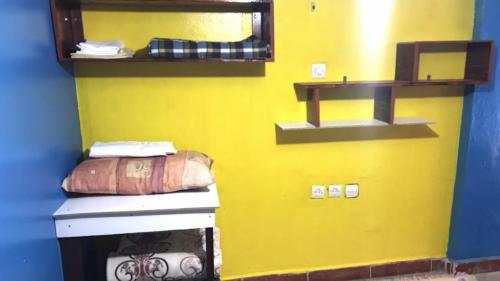 a room with a yellow wall with shelves on it at Studio tan tan in Tan-Tan Plage