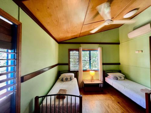 two beds in a room with green walls and a ceiling at Kwila Cottage in Mission Beach