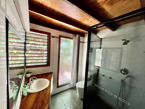 a bathroom with a glass shower and a sink at Kwila Cottage in Mission Beach