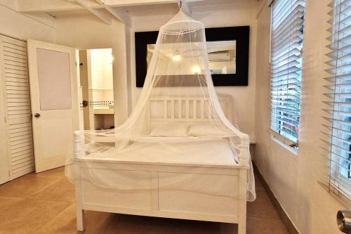 ein weißes Bett mit Baldachin in einem Zimmer in der Unterkunft Cozy Beachfront Apartment with Bay views in East End