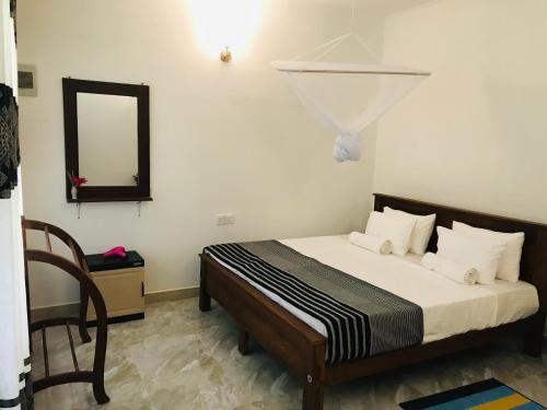 a bedroom with a bed with a mirror and a chair at Holly Flowers Villa in Sigiriya