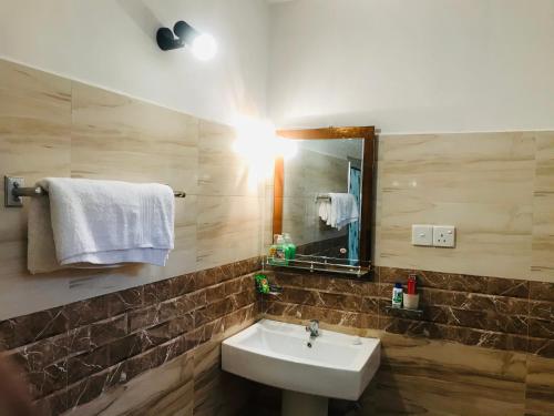 a bathroom with a sink and a mirror and towels at Holly Flowers Villa in Sigiriya