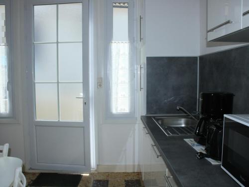 - une cuisine avec une porte blanche et un évier dans l'établissement Charmant T2 avec Terrasse Privée, à 600m Plage et Commerces, La Tranche-sur-Mer - FR-1-22-278, à La Tranche-sur-Mer
