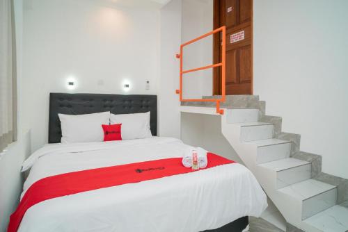a bedroom with a bed with a red blanket and a staircase at RedDoorz near Stasiun Senen in Jakarta