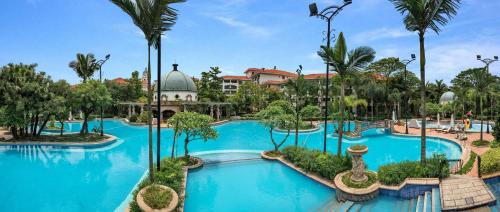 una piscina en un complejo con palmeras en Guangzhou Phoenix City Hotel en Zengcheng
