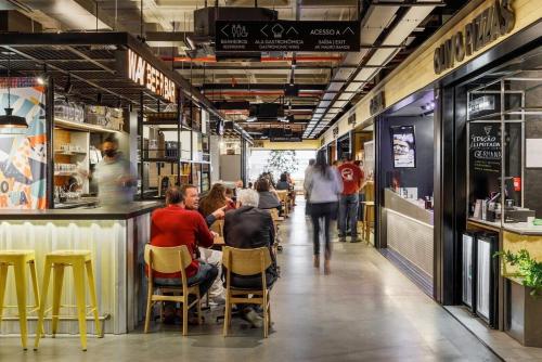 um grupo de pessoas sentadas numa mesa num restaurante em Patio Milano Apartamentos completos em condominio incrivel com food hall em Florianópolis