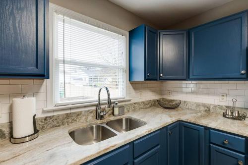 uma cozinha com armários azuis, um lavatório e uma janela em The Neighborhood House in Richmond em Richmond