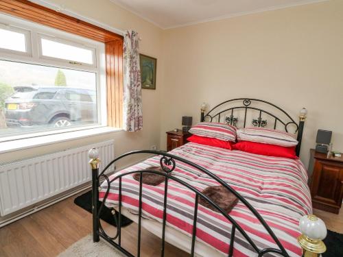 Schlafzimmer mit einem Bett mit roten Kissen und einem Fenster in der Unterkunft Cairn View in Arrochar