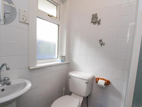 a white bathroom with a toilet and a sink at Cairn View in Arrochar