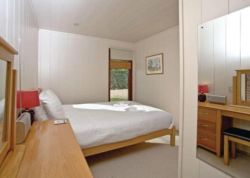 a bedroom with a bed and a desk and a window at Portmile Lodges in Cockwood