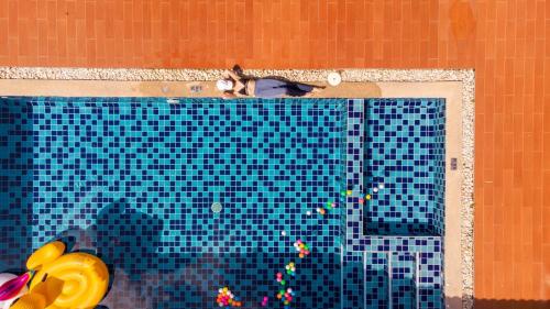 une personne assise au bord d'une piscine dans l'établissement The Legacy Huahin Pool Villa, à Hua Hin