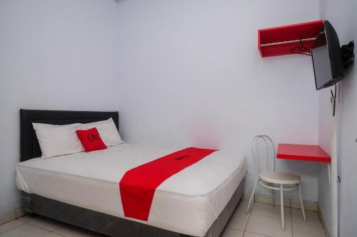 um quarto com uma cama com um cobertor vermelho e um banco em RedDoorz at Lapangan Bandara Sam Ratulangi Manado em Manado
