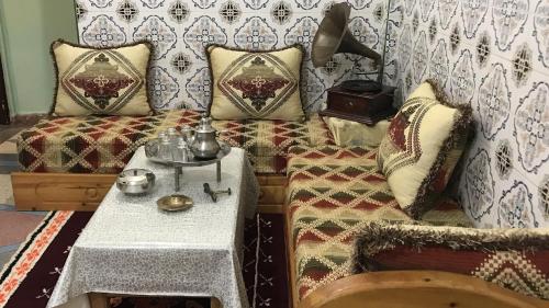 a room with a couch and a table with pillows at Maison d’hôtes ATLAS ait alla in Tan-Tan Plage