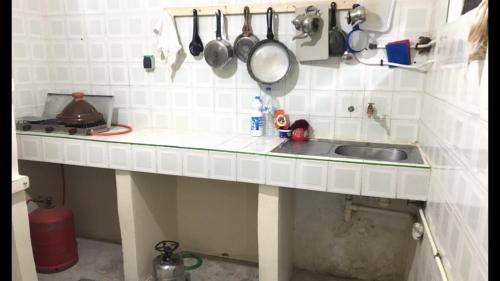 eine Küchentheke mit Spüle, Töpfen und Pfannen in der Unterkunft Maison d’hôtes ATLAS ait alla in Tan-Tan Plage