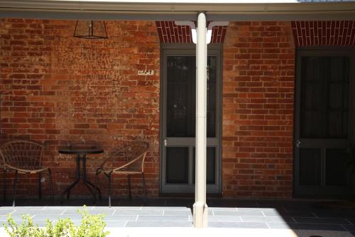 un bâtiment en briques avec une porte noire et une table dans l'établissement The Houston Wagga, à Wagga Wagga