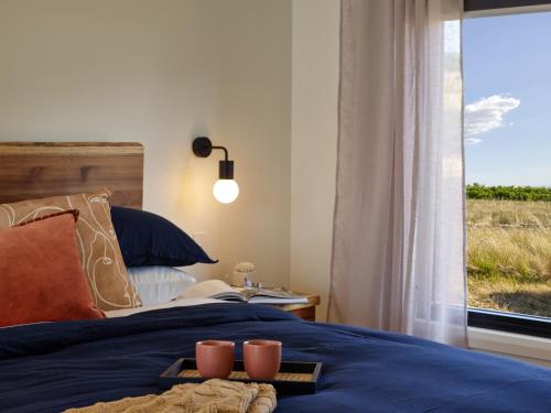 a bedroom with a bed with a window and two candles at Glenbosch Wine Estate Farm Stays in Beechworth