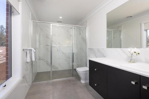 a bathroom with a glass shower and a toilet at Contemporary Living in the CBD in Wagga Wagga