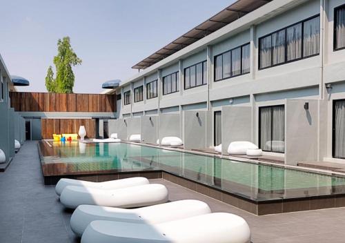 a building with a swimming pool with white chairs at S Ratchada Leisure Hotel - SHA PLUS in Bangkok