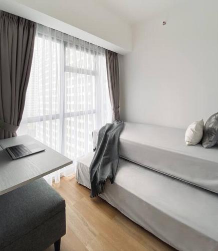 a bedroom with a bed and a desk and a window at Cozy Japandi 2BR at Gading Serpong near BSD in Pumpangsineng