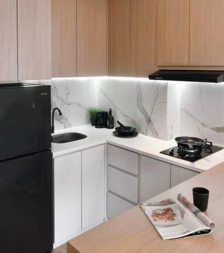 a kitchen with a black refrigerator and a sink at Cozy Japandi 2BR at Gading Serpong near BSD in Pumpangsineng