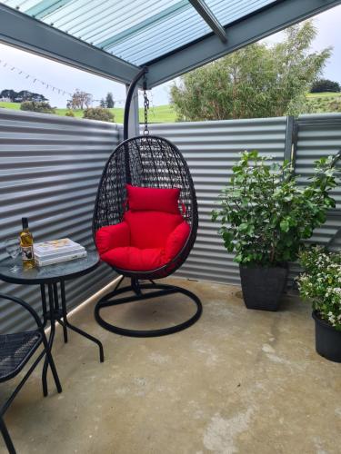 ein rotes Kissen auf einem Stuhl auf einer Terrasse in der Unterkunft Kadi House - Unit 2 in Wynyard