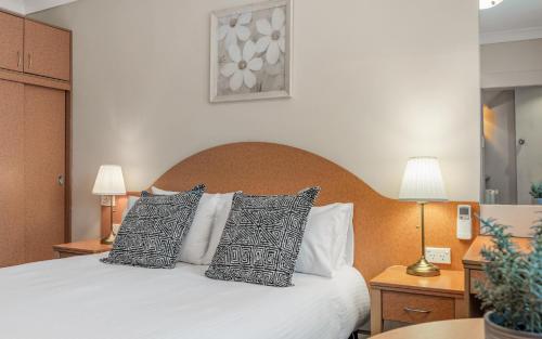 a bedroom with a white bed with pillows at Blue Mountains Heritage Motel in Katoomba