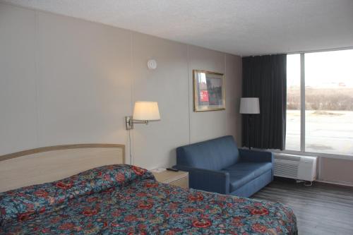 a hotel room with a bed and a blue chair at Red Carpet Inn - Louisville in Louisville