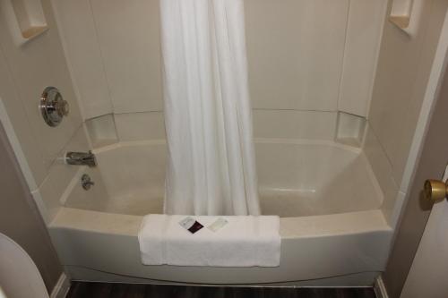 a bathroom with a shower with a white shower curtain at Red Carpet Inn - Louisville in Louisville