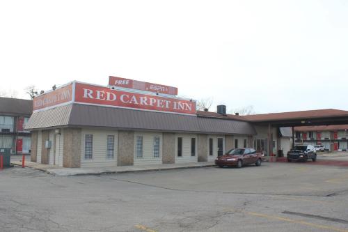 a red car parked in front of a building at Red Carpet Inn - Louisville in Louisville
