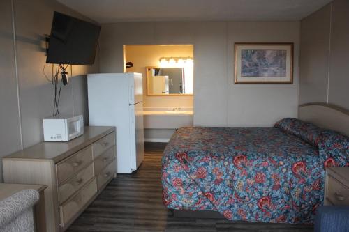 ルイスビルにあるRed Carpet Inn - Louisvilleのベッドと冷蔵庫が備わるホテルルームです。