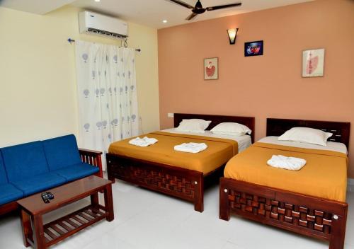 a bedroom with two beds and a blue chair at Nilton Bay Residency in Puducherry