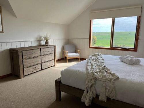 a bedroom with a bed and a dresser and a window at Banksia in Port Campbell