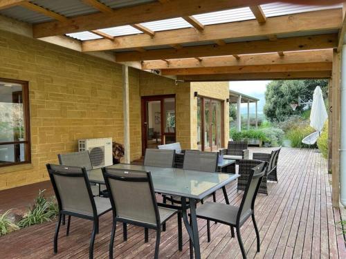 a patio with a table and chairs on a deck at Banksia in Port Campbell