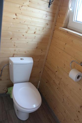 e bagno con servizi igienici bianchi su una parete in legno. di Chatka Pod Bukovkou a Červená Voda