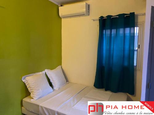 - une petite chambre avec un lit et un rideau bleu dans l'établissement PIA HOME La Pompe, à Mamoudzou