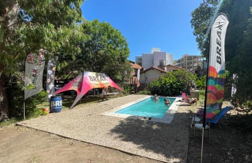 una piscina con sombrilla y gente en ella en Panorama Villa Gesell en Villa Gesell
