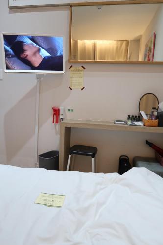 a bedroom with a bed and a tv on the wall at Andong Poong-gyung HOSTEL n LIBRARY in Andong